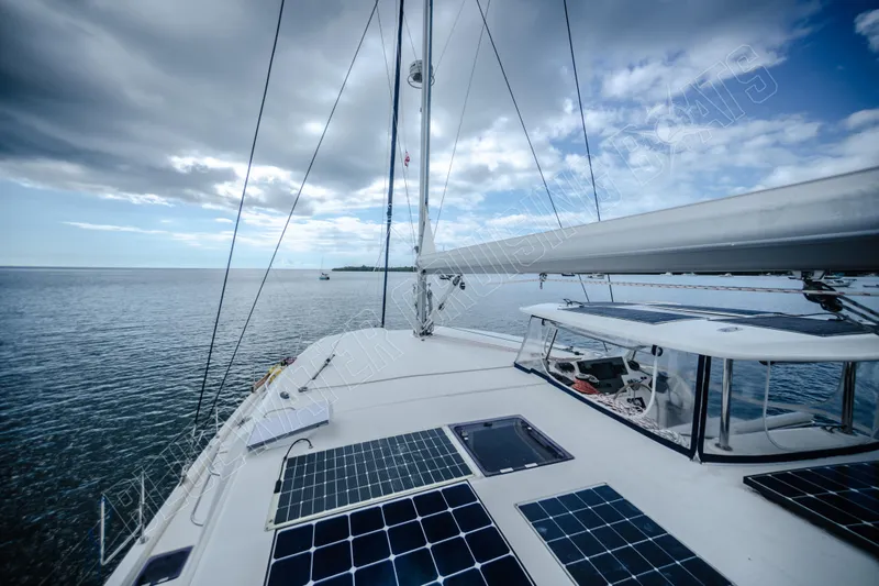 Purple Pearl Yacht Photos Pics 2015 Leopard 48 catamaran with solar panels sailing on a calm sea under cloudy skies.
