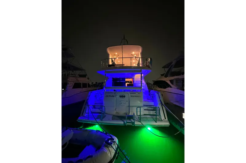 My Reality Yacht Photos Pics 2012 Neptunus 62 Flybridge yacht illuminated at night with vibrant blue and green lights.