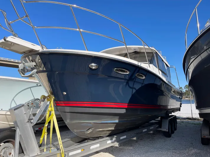  Yacht Photos Pics 2019 Cutwater C-302 Coupe boat on trailer, blue hull with red stripe, under clear sky.