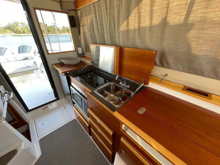  Yacht Photos Pics 2019 Cutwater C-302 Coupe kitchen with stove, sink, and wooden cabinetry.