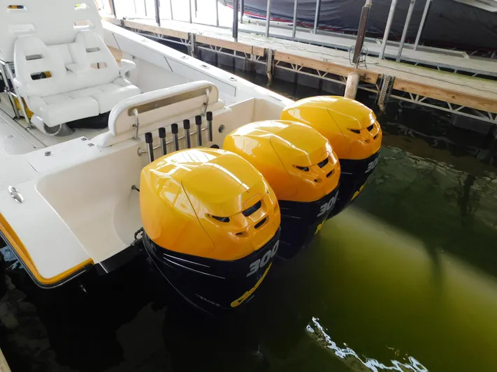 Fountain Repowered Yacht Photos Pics 2004 Fountain 38 Sportfish CC with triple yellow outboard engines docked in water.