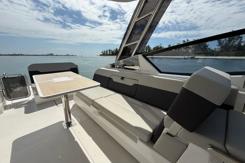  Yacht Photos Pics 2025 Aquila 32 Sport boat interior with seating and table, overlooking serene water.