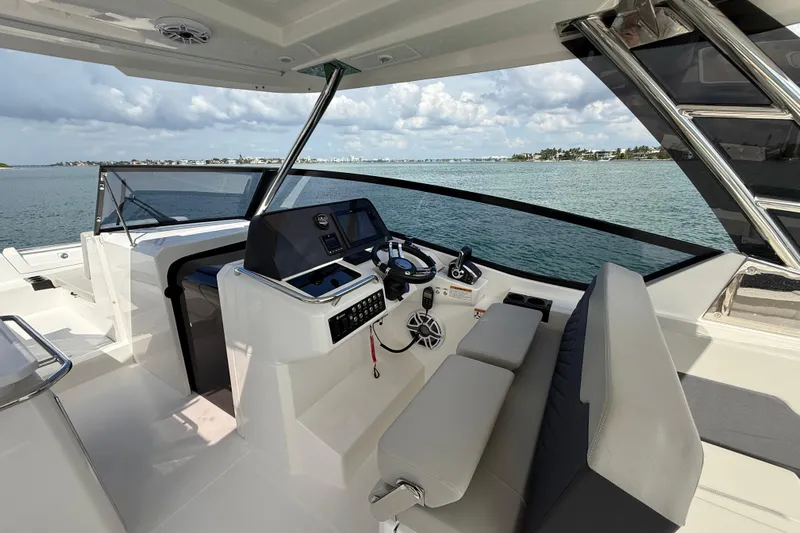  Yacht Photos Pics 2025 Aquila 32 Sport yacht helm with modern controls, overlooking serene waters.