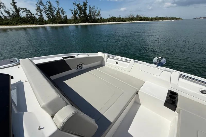  Yacht Photos Pics 2025 Aquila 32 Sport boat interior with seating, on calm water near a tree-lined shore.