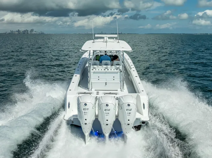  Yacht Photos Pics 2025 Contender 44 ST boat cruising on open water, rear view with powerful engines.