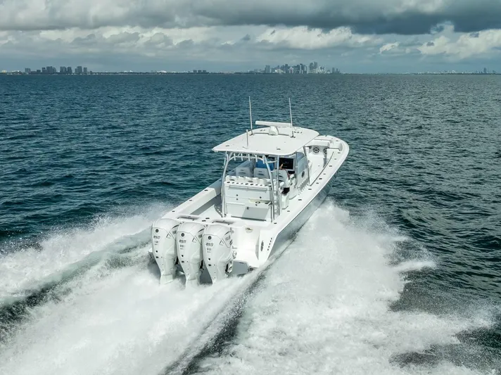  Yacht Photos Pics 2025 Contender 44 ST boat cruising on open water with city skyline in background.
