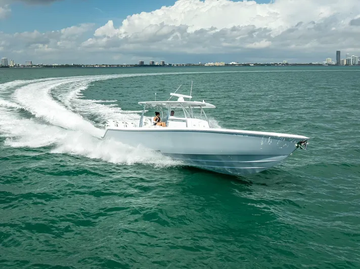  Yacht Photos Pics 2025 Contender 44 ST boat cruising on open water with city skyline in background.