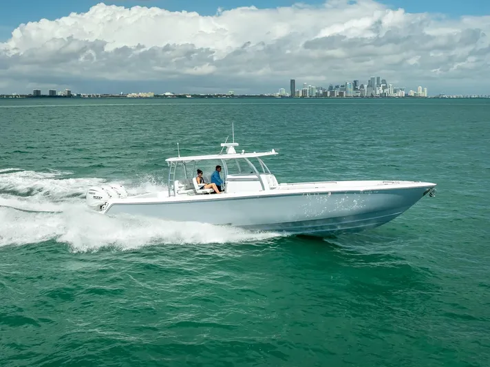  Yacht Photos Pics 2025 Contender 44 ST boat cruising on open water with city skyline in background.