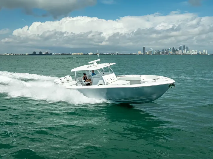  Yacht Photos Pics 2025 Contender 44 ST boat cruising on open water with city skyline in background.
