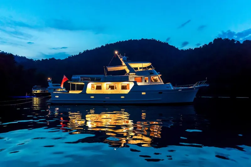Perseus Yacht Photos Pics Luxurious 2004 Fleming 75 yacht illuminated on serene water at dusk.