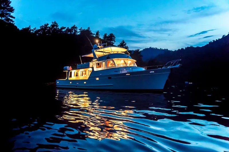Perseus Yacht Photos Pics Luxurious 2004 Fleming 75 yacht illuminated on serene water at dusk.