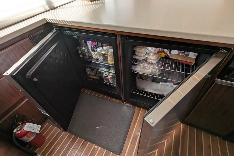 Mas Fina Yacht Photos Pics 1987 Hatteras Convertible yacht kitchen with open mini fridge, stocked with food and drinks.