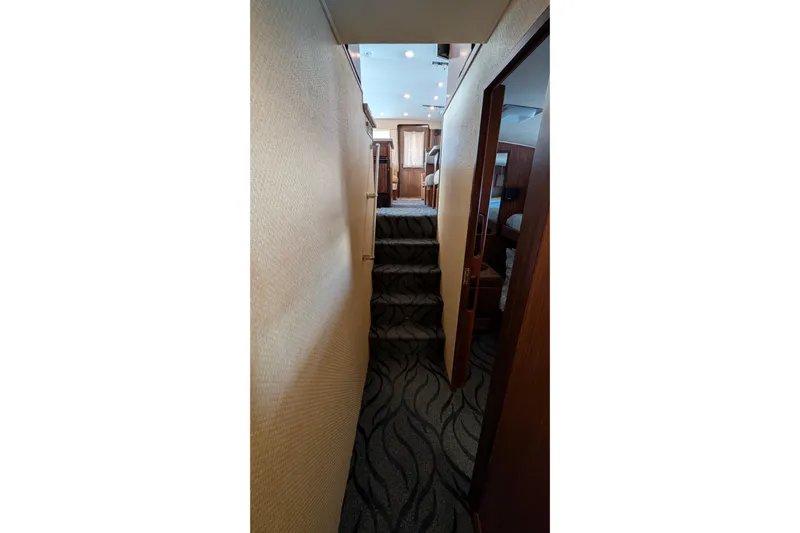 Mas Fina Yacht Photos Pics Interior hallway of 1987 Hatteras Convertible yacht with carpeted stairs and wood accents.