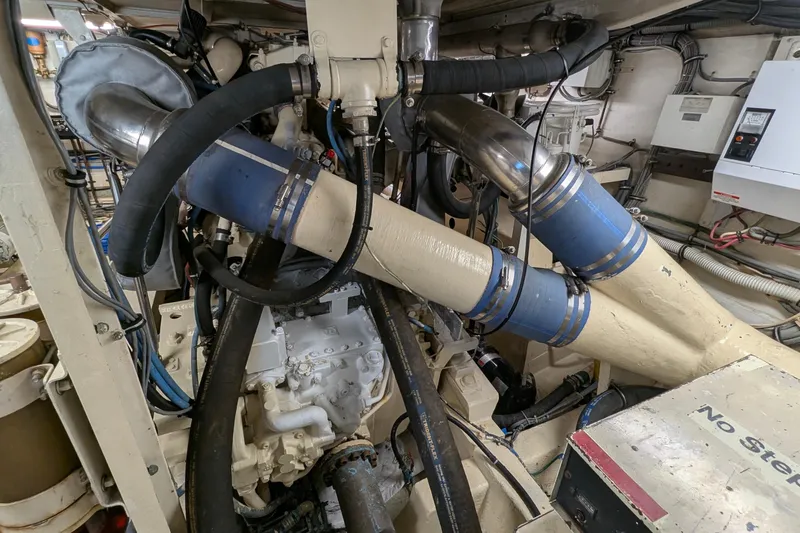 Mas Fina Yacht Photos Pics Engine room of a 1987 Hatteras Convertible boat with visible pipes and machinery.