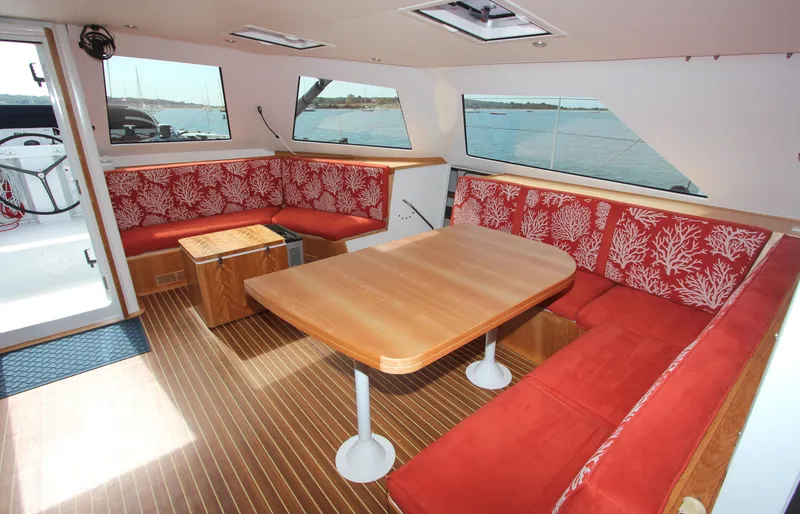 Saphira Yacht Photos Pics Luxurious interior of 2018 Chris White Atlantic 70 "SAPHIRA" with red seating and wooden table.