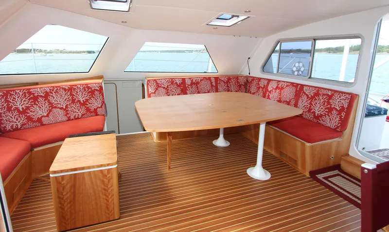 Saphira Yacht Photos Pics Interior of 2018 Chris White Atlantic 70 "SAPHIRA" with red floral seating and wooden table.