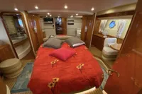 Luxurious 2007 Azimut 68E yacht bedroom with red floral bedding and elegant wood finishes.