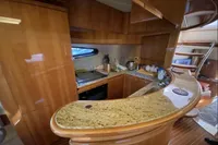 Luxurious kitchen interior of 2007 Azimut 68E yacht with wooden cabinetry and granite countertops.