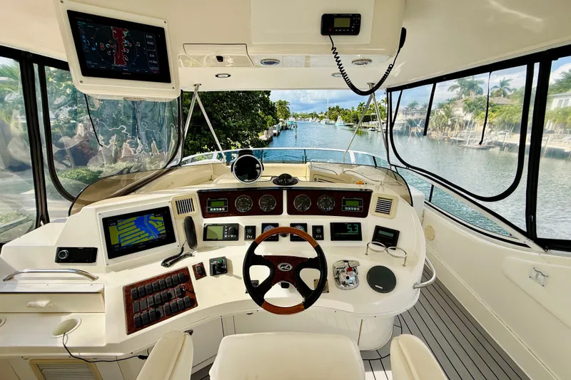 Rogue One Yacht Photos Pics Helm of 2003 Sea Ray 560 Sedan Bridge yacht with navigation equipment and scenic waterway view.
