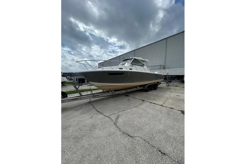  Yacht Photos Pics 2020 Pursuit OS 325 Offshore boat on trailer, parked outdoors under cloudy sky.