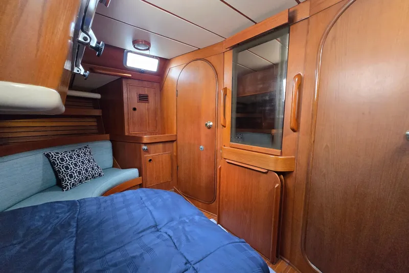 Name Reserved Yacht Photos Pics Cozy cabin interior of 1985 Nautor Swan 46 yacht with wooden finish and blue bedding.