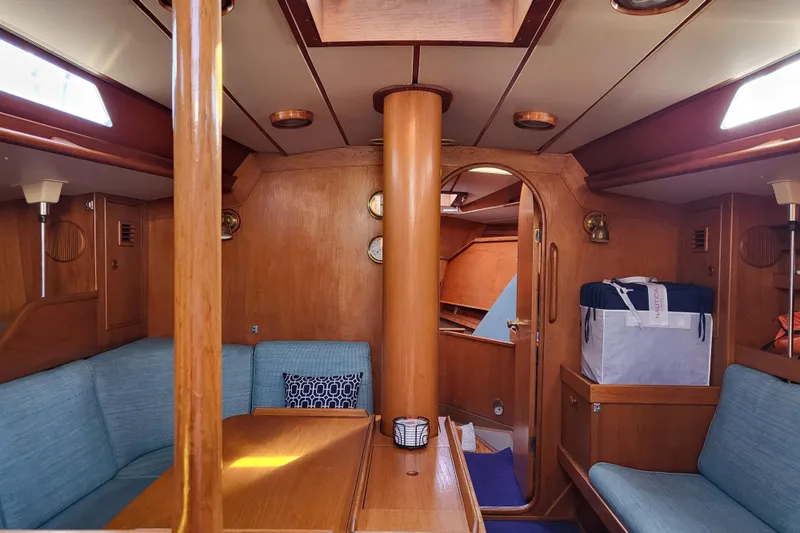 Name Reserved Yacht Photos Pics Interior of 1985 Swan 46 yacht with wooden furnishings and blue seating.