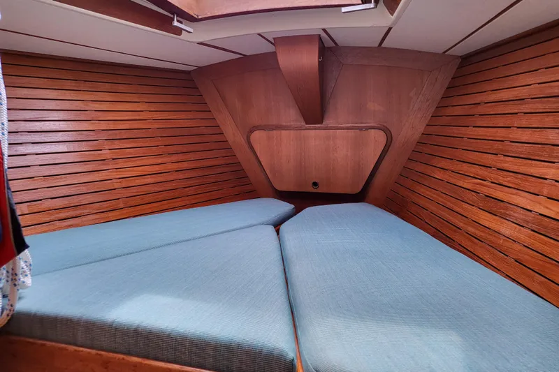 Name Reserved Yacht Photos Pics Interior cabin of 1985 Swan 46 yacht with wooden paneling and blue cushions.