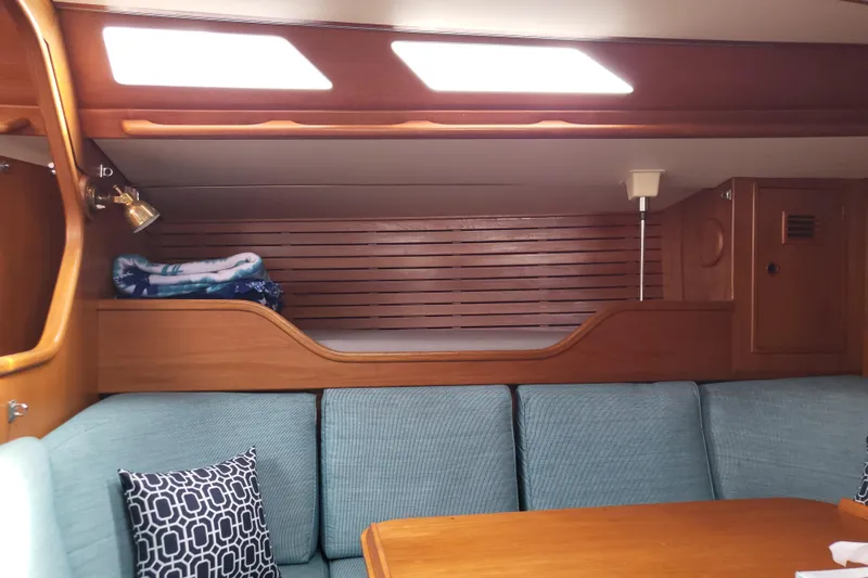 Name Reserved Yacht Photos Pics Interior of 1985 Swan 46 yacht with wooden paneling and blue seating.