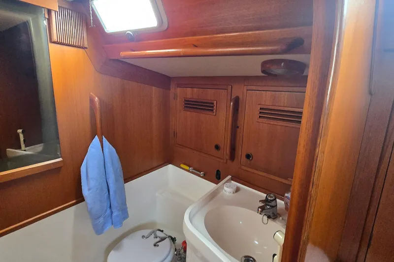 Name Reserved Yacht Photos Pics 1985 Swan 46 yacht bathroom with wooden cabinets, sink, and blue towel.