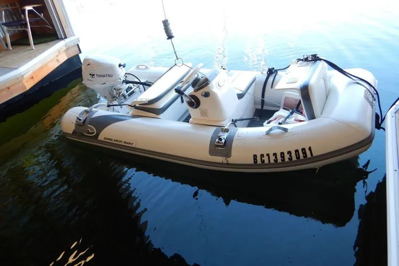  Yacht Photos Pics Inflatable boat with Tohatsu motor docked in calm water.