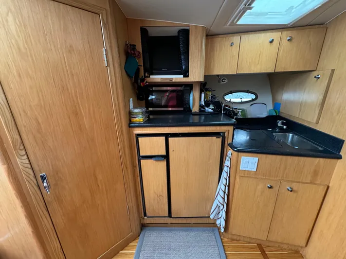 Vixen Yacht Photos Pics 2002 Tiara Yachts 3500 Express galley with wood cabinetry and black countertops.