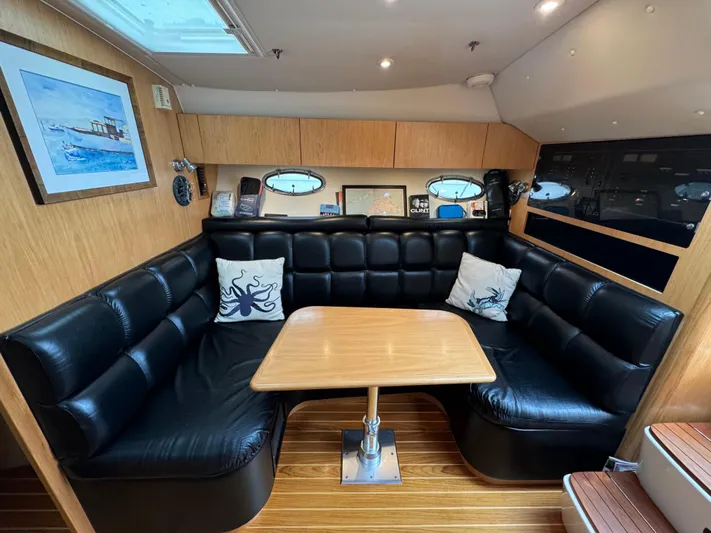 Vixen Yacht Photos Pics 2002 Tiara Yachts 3500 Express interior with black leather seating and wooden table.
