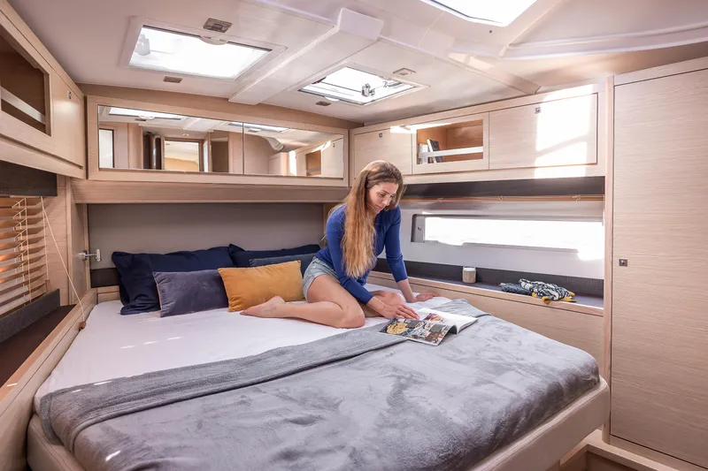 New Stock Boat - Available Now Yacht Photos Pics Woman reading in a luxurious cabin of a 2023 Dufour 470 yacht.