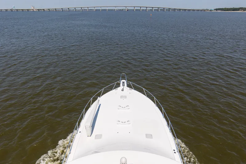 Reel Blues Yacht Photos Pics Bow view of 2007 Viking 64 Enclosed Bridge yacht on open water near a bridge.