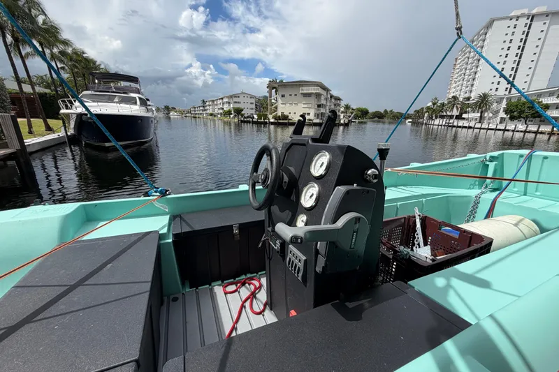 Calacoto Yacht Photos Pics 2023 Royal Cape Catamarans Majestic 530 cockpit with steering wheel, docked near waterfront buildings.