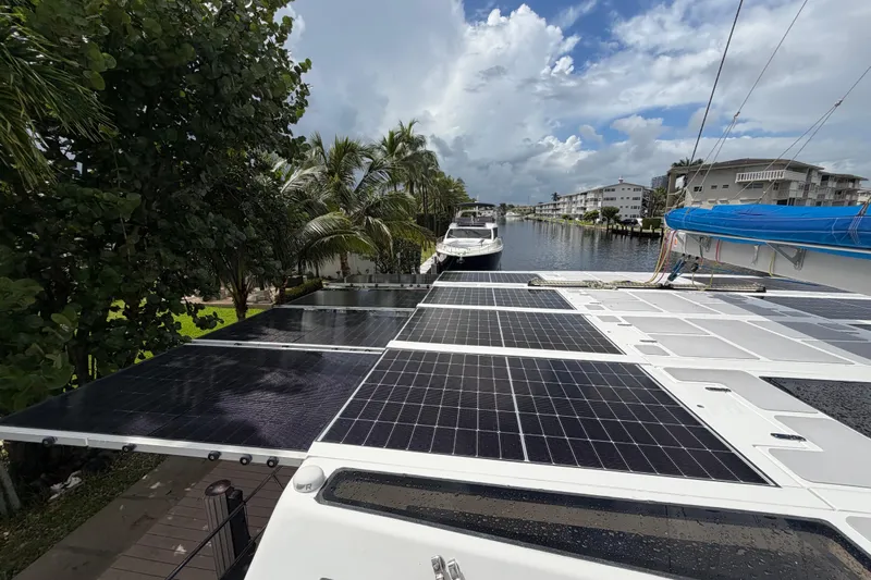 Calacoto Yacht Photos Pics 2023 Royal Cape Catamarans Majestic 530 with solar panels, docked near palm trees and waterway.
