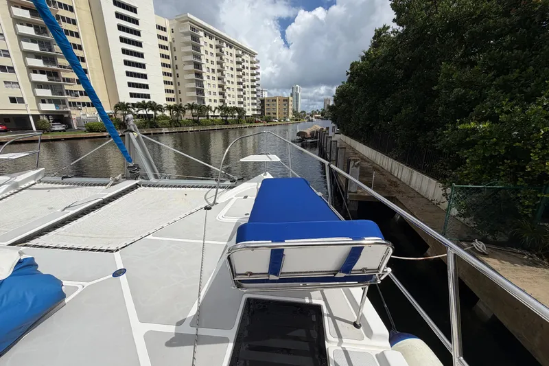 Calacoto Yacht Photos Pics 2023 Royal Cape Catamarans Majestic 530 docked near waterfront buildings and lush greenery.