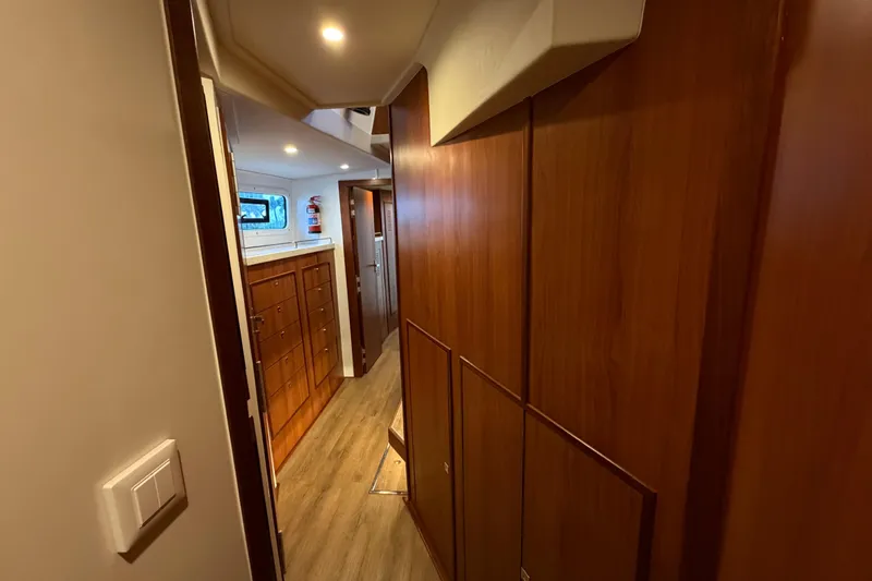 Calacoto Yacht Photos Pics Interior hallway of 2023 Royal Cape Catamarans Majestic 530, featuring wooden cabinetry and modern lighting.