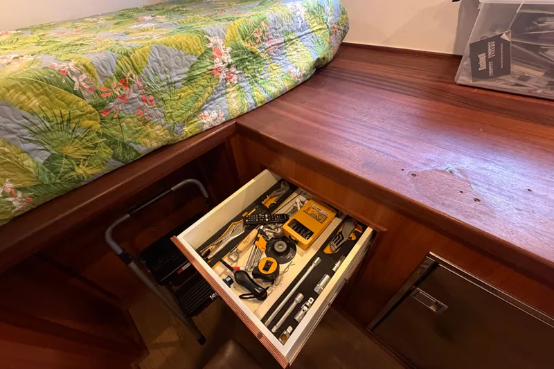 Calacoto Yacht Photos Pics Drawer with tools in a 2023 Royal Cape Catamarans Majestic 530 cabin, floral bedspread visible.