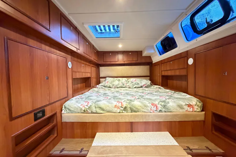 Calacoto Yacht Photos Pics Luxurious cabin interior of 2023 Royal Cape Catamarans Majestic 530 with wood paneling and floral bedding.