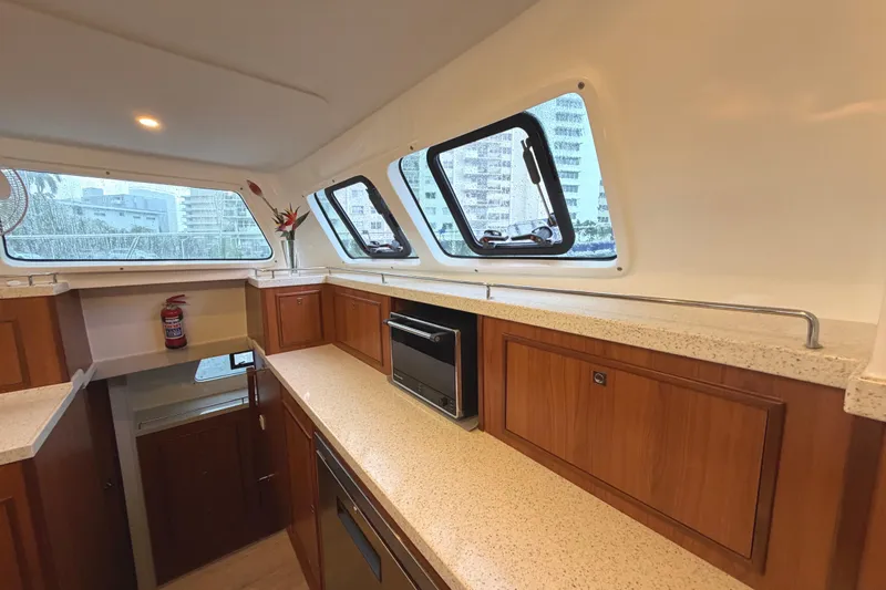 Calacoto Yacht Photos Pics Interior of 2023 Royal Cape Catamarans Majestic 530, featuring modern kitchen with wood cabinetry.