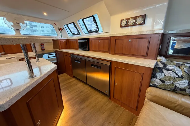 Calacoto Yacht Photos Pics Luxurious 2023 Royal Cape Catamarans Majestic 530 interior with modern kitchen and wood cabinetry.