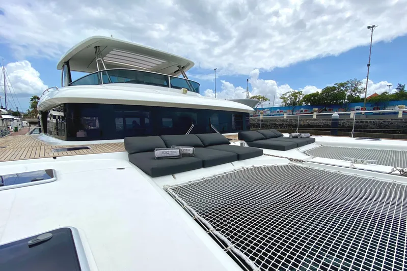  Yacht Photos Pics 2017 Lagoon 630 Motor Yacht with sun loungers and netted deck, docked under a cloudy sky.
