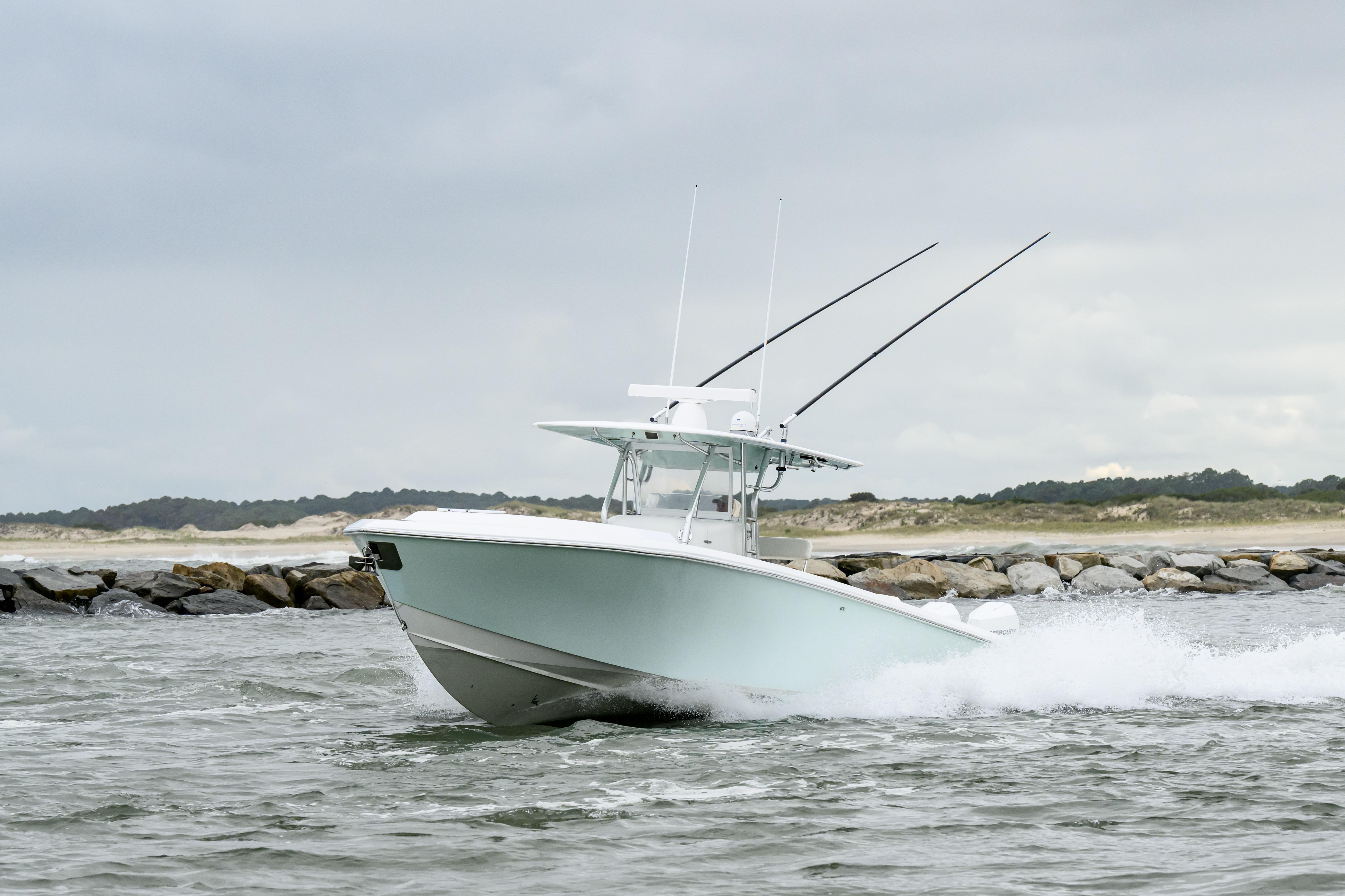 2008 Venture 39 Cuddy boat navigating through waves near rocky shoreline.