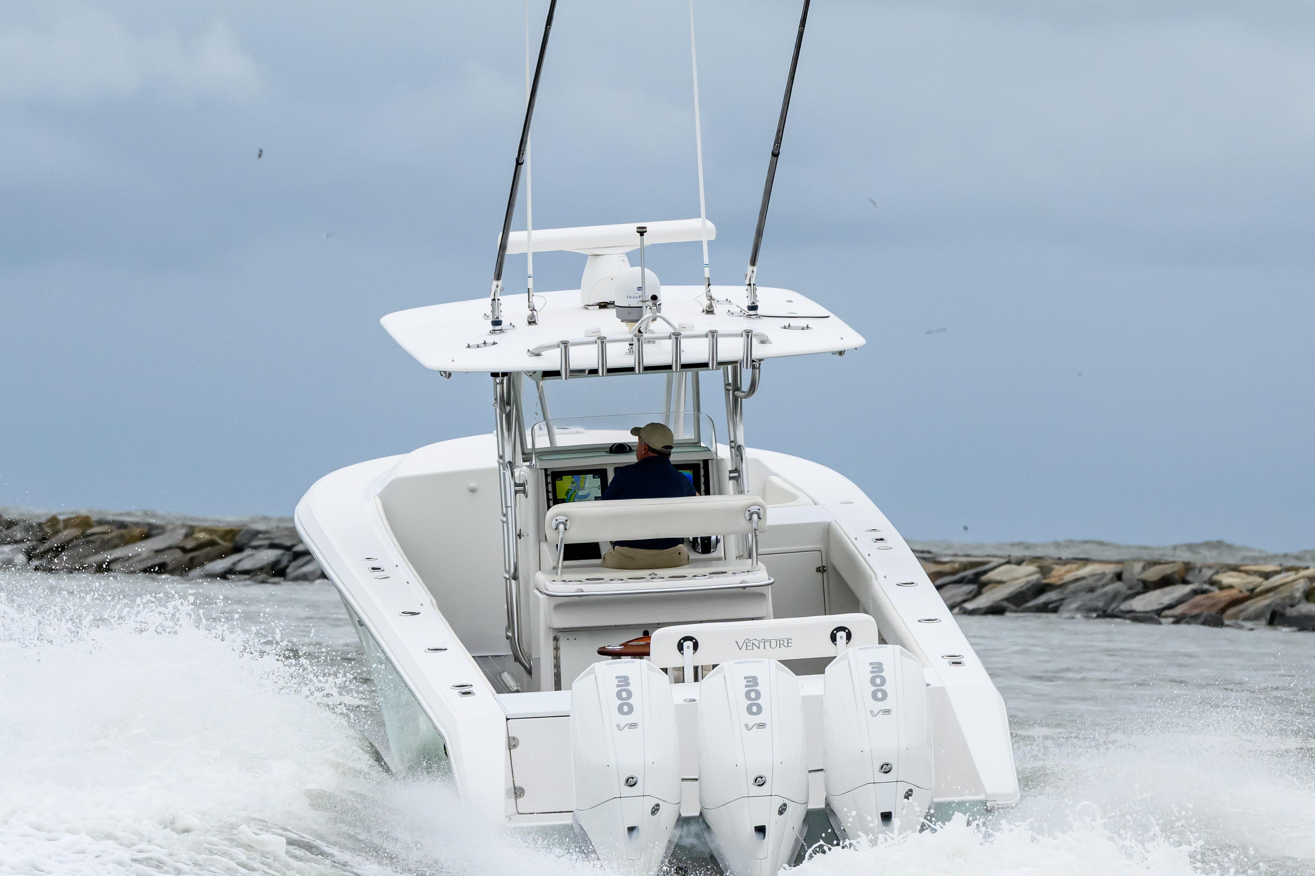 2008 Venture 39 Cuddy boat navigating through waves near rocky shoreline.
