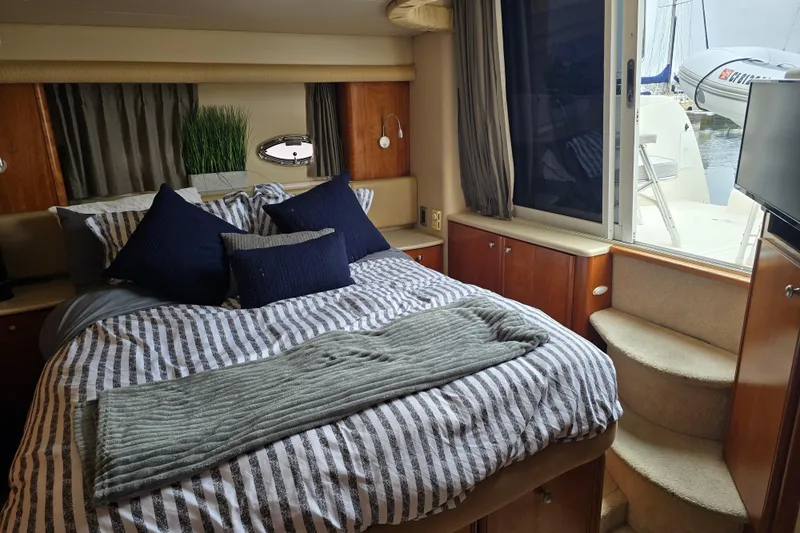 Embracing Life Yacht Photos Pics Luxurious bedroom interior of 2004 Meridian 459 Motoryacht with striped bedding and outdoor view.