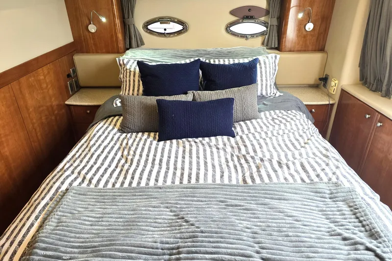 Embracing Life Yacht Photos Pics Luxurious bedroom interior of 2004 Meridian 459 Motoryacht with striped bedding and plush pillows.