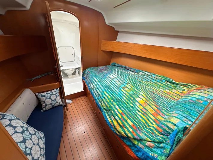 Pacifico Yacht Photos Pics Cozy cabin interior of 2005 Beneteau First 44.7 sailboat with colorful bedding and wooden finish.