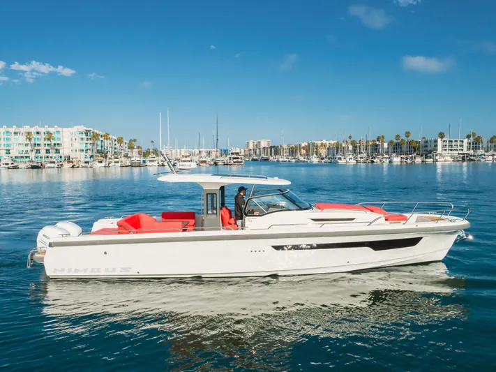 Intrepid Yacht Photos Pics 2021 Nimbus T11 boat cruising in a marina with modern buildings in the background.
