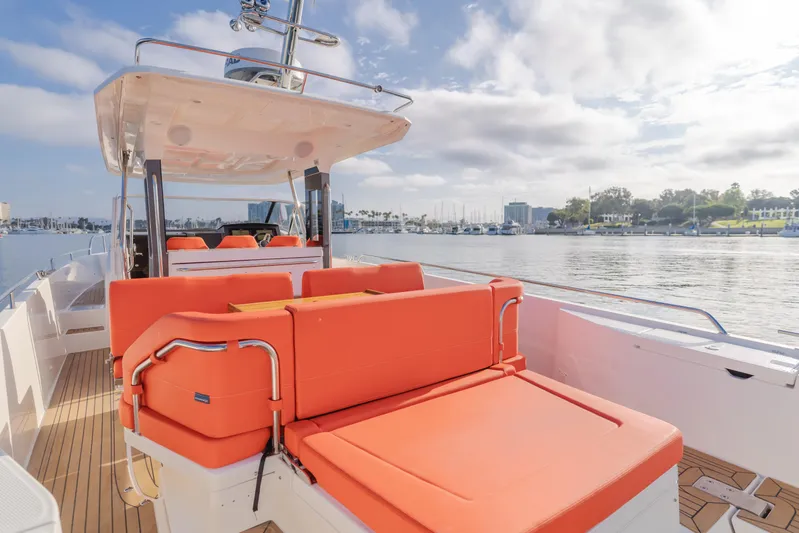 Intrepid Yacht Photos Pics Luxurious 2021 Nimbus T11 boat with vibrant orange seating, docked by a serene waterfront.